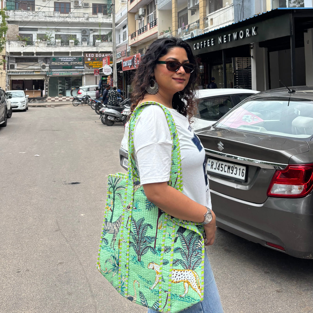 Woman holding a green patterned bag on a street with buildings and cars in the background